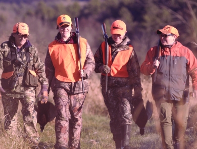 Four hunters in blaze orange walking after a pheasant hunt