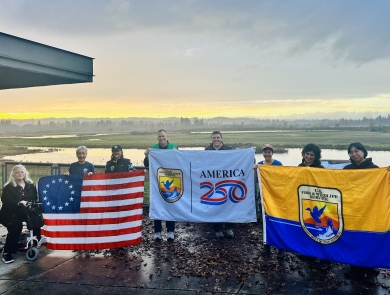 8 people in front of wetland holding 3 flags, Betsy Ross US flag at left