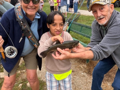 Child posing with volunteers holding fish