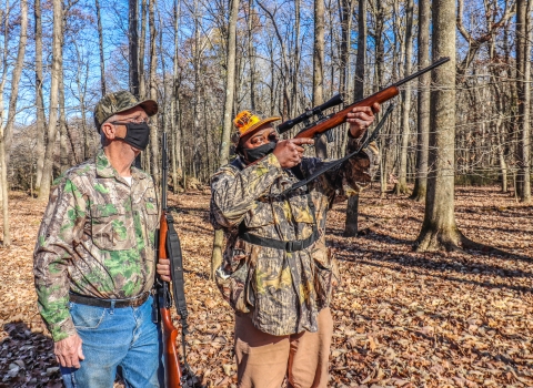 An image of two people in the woods hunting.