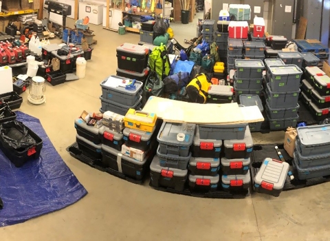 gear organized into plastic containers stored in a warehouse