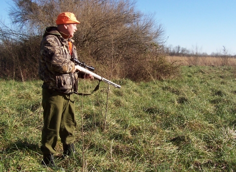 Gun hunter walking across field