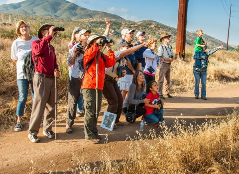 Visitors on a ranger-led hike point and react to a wildlife sighting at San Diego National Wildlife Refuge.