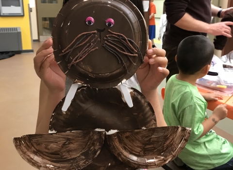 Child holds walrus mask up to face. 