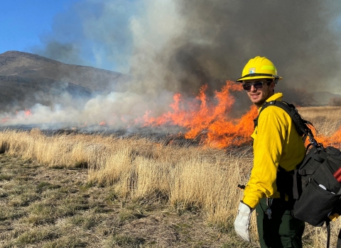 Photo of a FWS firefighter next to a prescribed burn by USFWS. 