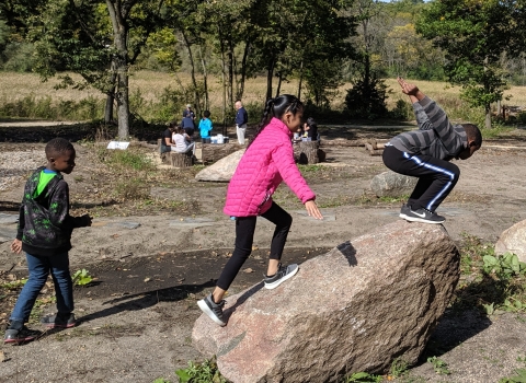 Children jumping off rock while playing