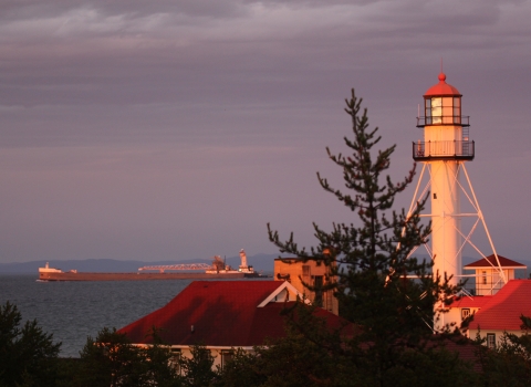 The lighthouse at Whitefish Point in Michigan with a freighter on Lake Superior and Canada in the background. 