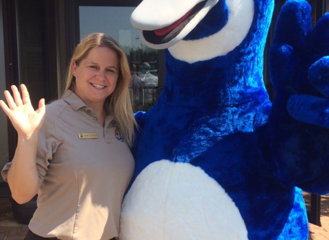 woman in FWS uniform smiles next to blue goose mascot
