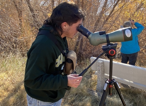 Man looking through scope to find birds