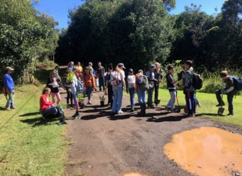 Student and volunteers stand along a dirt road. 