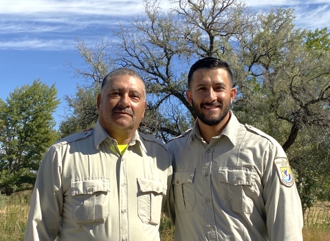 Two men in Service uniforms smiling in an outdoor setting