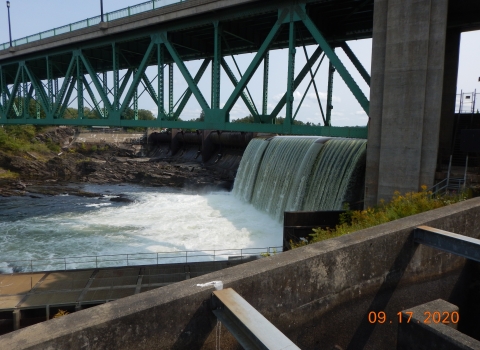 Image of dam with bridge overhead and fish passage structures in the foreground