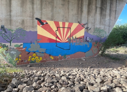 Mural of the Arizona state flag with insert of outline of Arizona on bridge underpass.