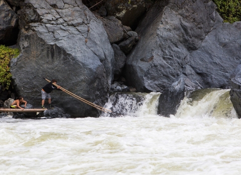 two men use dip nets to fish at waterfall