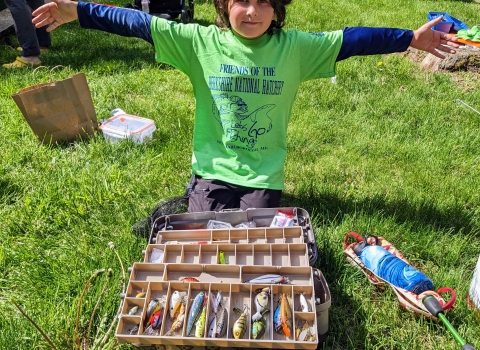 Kid kneeling in front of a tackle box with fishing lures inside