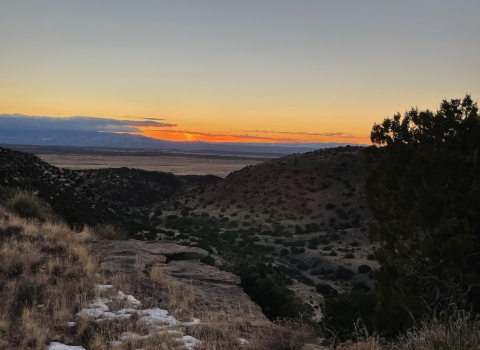 a view of sunset from the top of a ridge across an arid landscape