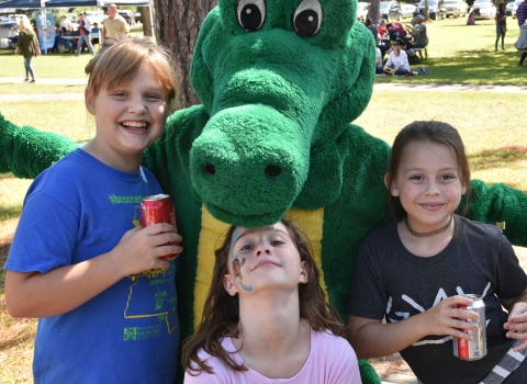 Alligator mascot poses with three girls at event