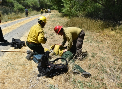 Firefighters tend to a patient with a heat illness during a practice scenario.