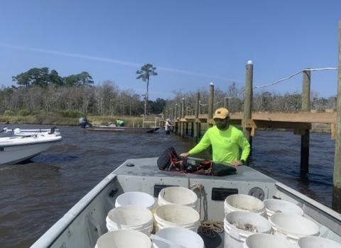 Biologist prepares boat with rock and oyster shell