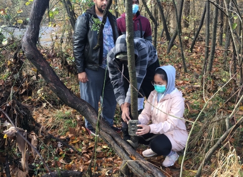 students setting up trail camera in the woods