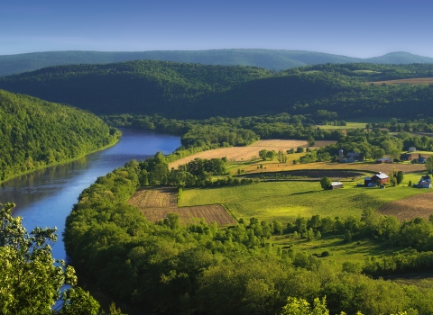 a river winds through lush farm land and rolling hills