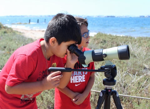 Two young boys use a spotting scope 