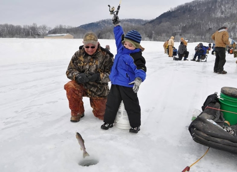 Young boy enjoying icing as he holds up his catch.