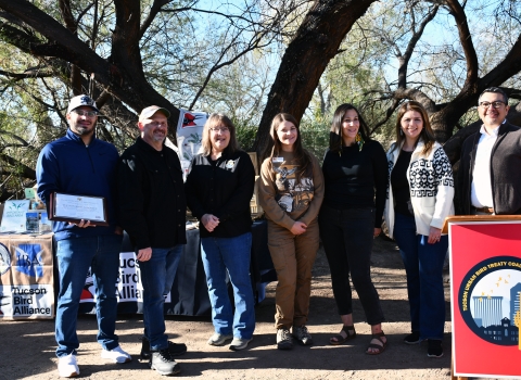 seven people stand together smiling in front of a podium that says Tucson urban bird treaty coaltion