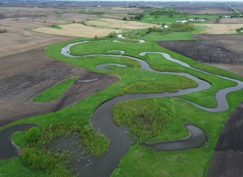 An aerial landscape image showing small, interconnected, crescent‑shaped wetlands surrounded by lush green vegetation.