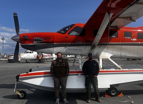 two pilot biologist standing by a plane