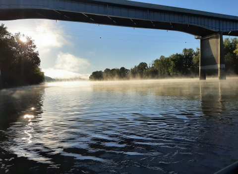 A bridge spans a foggy river below