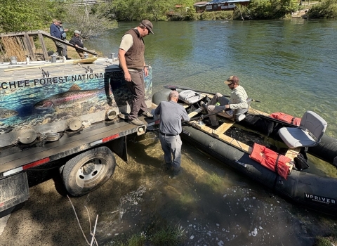 Service staff transfer trout from a stocking truck to a raft.