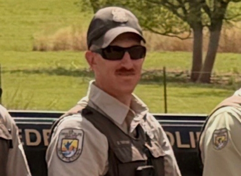 Officer David Taylor, standing with hands held at his waist, alongside other officers.