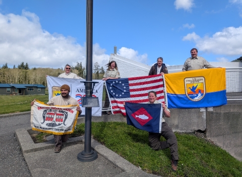 6 people on hill holding 4 flags, fish pennant